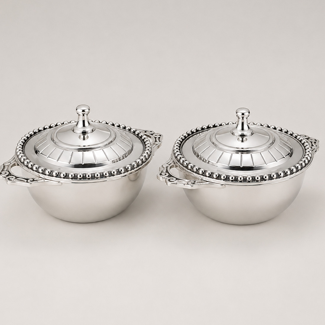 Pair of polished metal serving bowls with lids