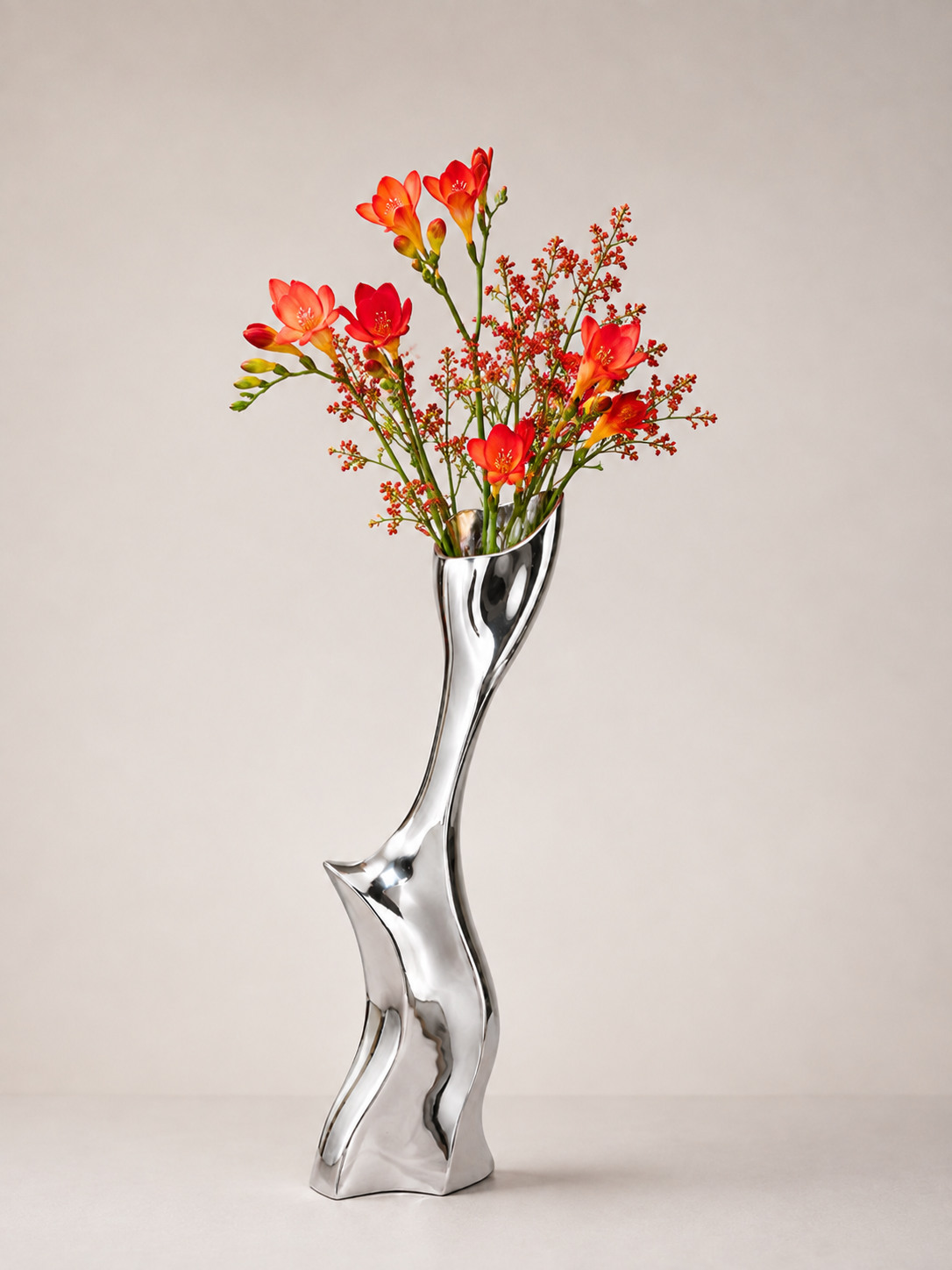 Sculptural silver flower vase with orange blooms